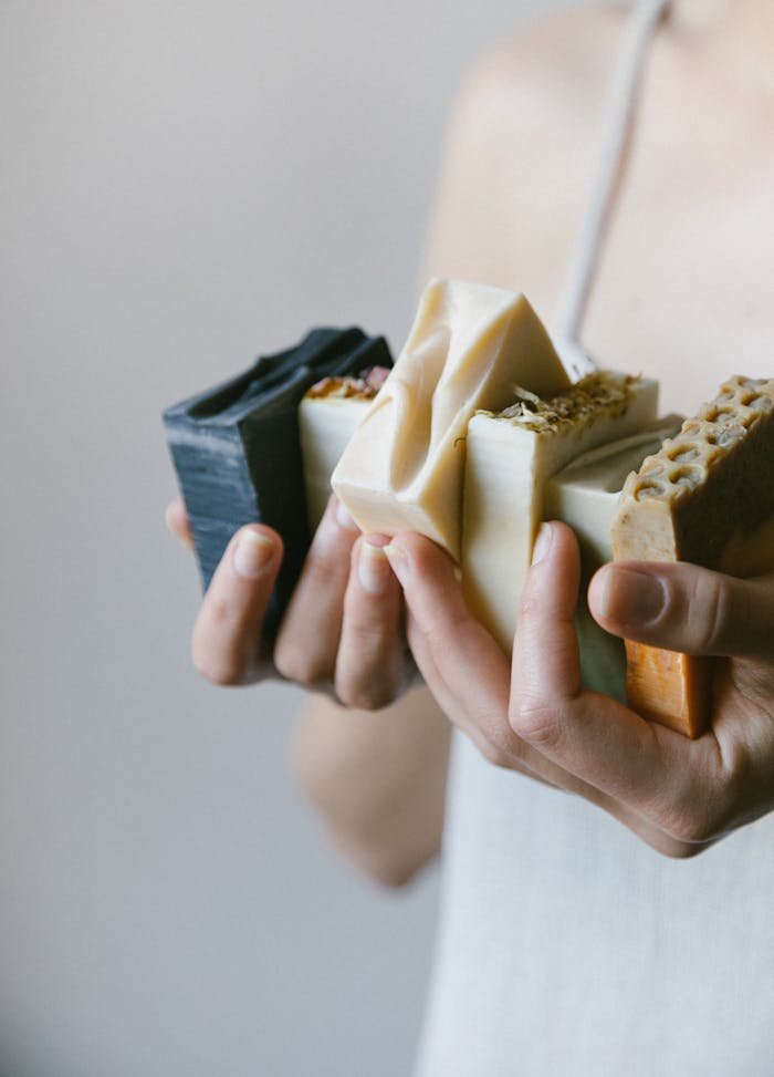 Close-up of hands holding diverse organic soaps in a delicate skin care setting.