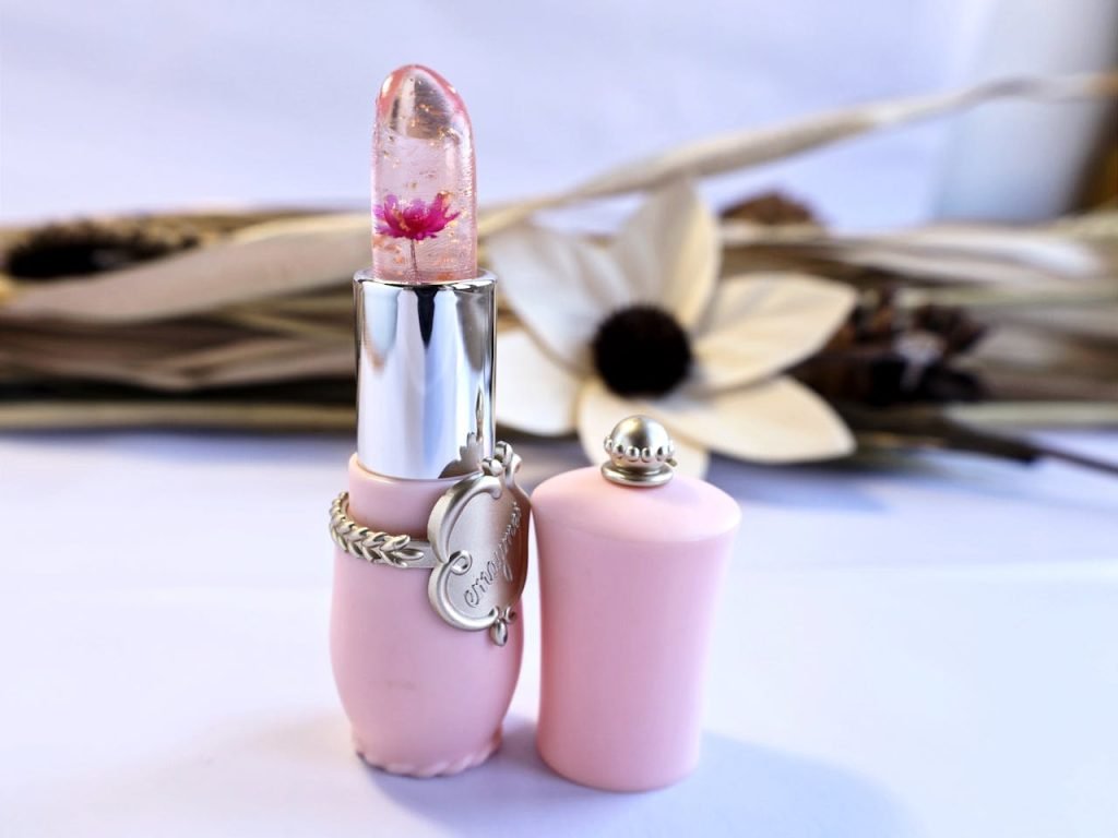 A unique pink lipstick with an embedded flower and stylish container, perfect for cosmetics lovers.